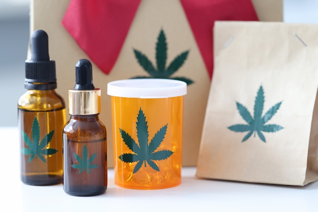 Marijuana pills and bottles with extract standing on background of gift