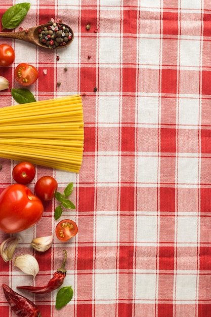 Marinara pasta-ingrediënten liggen op een geruit tafelkleed. rauwe tagliatelle met kruiden en kleine kerstomaatjes.
