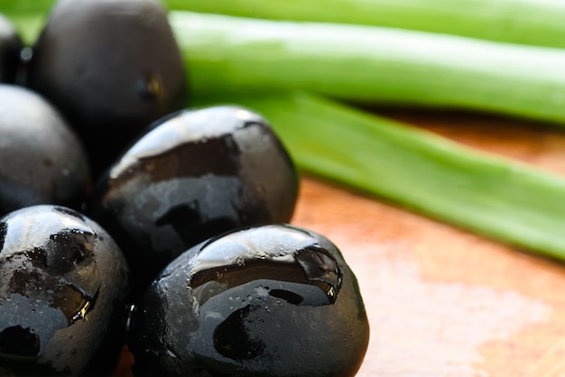 Marinated black olives on wooden background