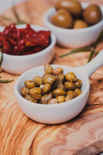 Marinated capers - in a white saucer on a board