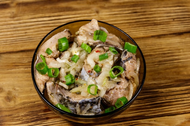 Marinated carp in glass bowl on wooden table