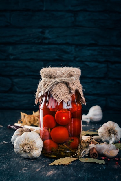 Marinated cherry tomatoes in a jar Stocks of food Top view On a wooden background Copy space