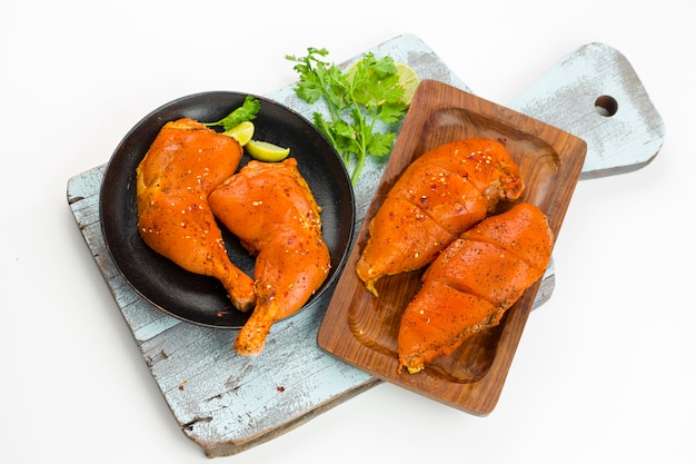 Marinated  chicken legs and breast fillet which is placed on painted cutting board