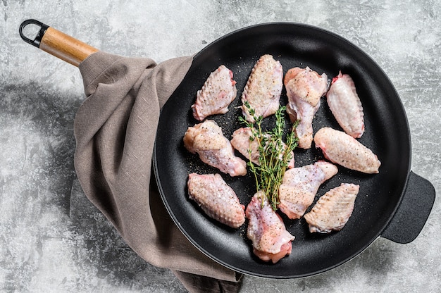 Marinated chicken wings with spices and herbs in a pan.