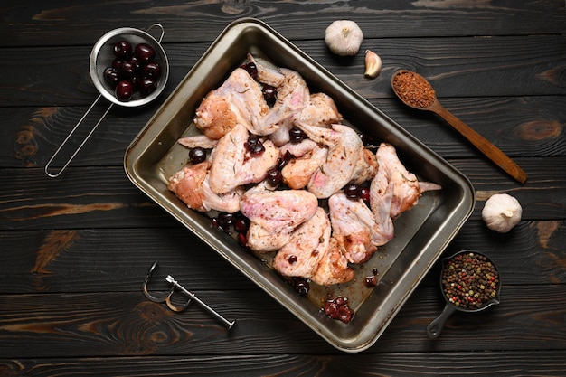 Marinated chicken wings with sweet cherry on a rustic wooden background