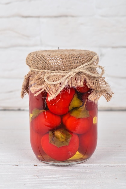 Marinated chili peppers in a jar Stocks of food Top view On a wooden background Copy space