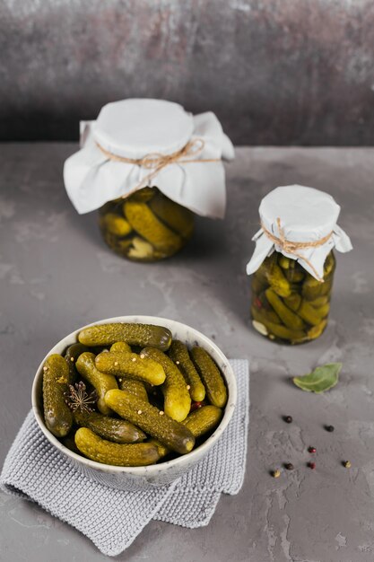 Marinated cucumbers gherkins with dill and garlic in glass jar on a grey concrete table