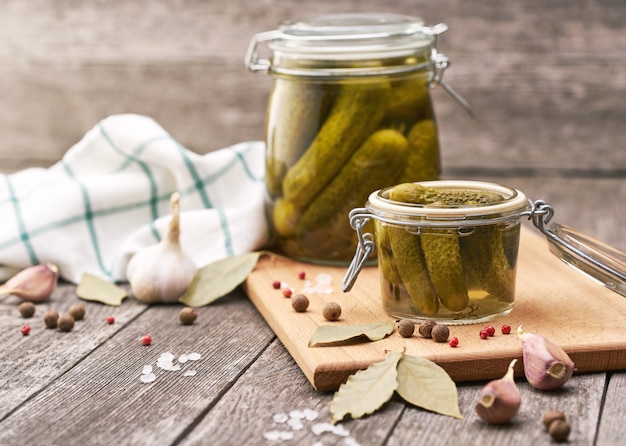 Marinated cucumbers with herbs and spices on wooden table. Jar of pickled homemade cucumbers.