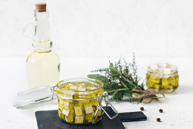 Marinated feta in a glass jar, spices and flavored olive oil on a wooden background