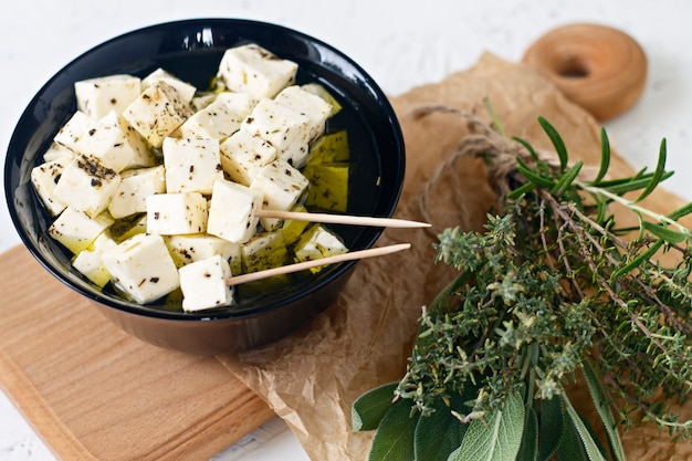 Marinated feta in a plate on a wooden board with spices on a white background