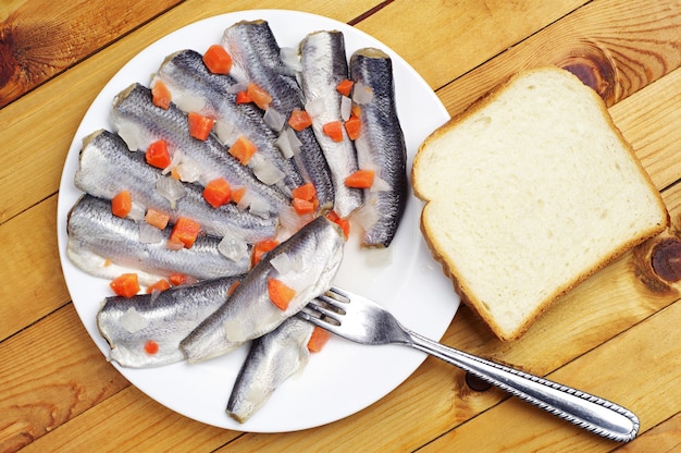 Marinated fish in a plate on wooden background. Top view