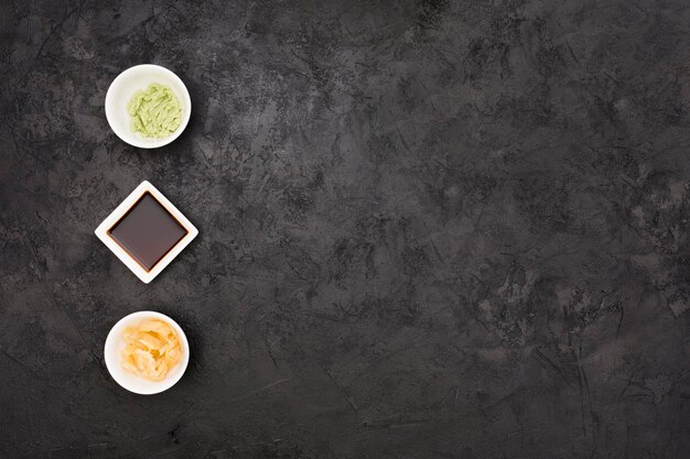 Photo marinated ginger soy sauce wasabi bowl arranged row textured black surface