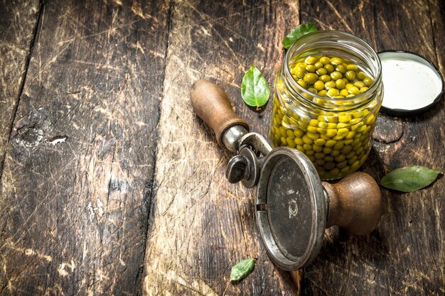 Marinated green peas with seamer on wooden table.