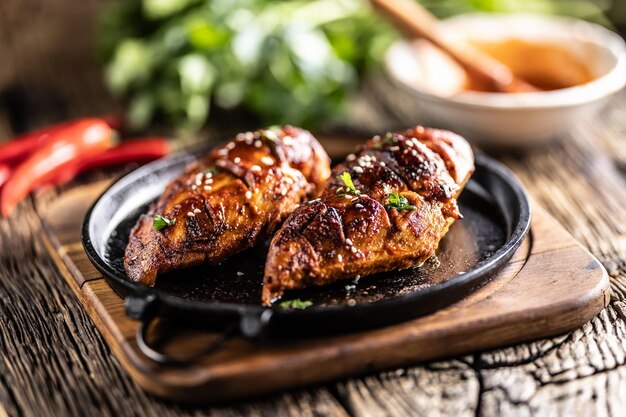 Marinated grilled chicken breast in BBQ sauce and served on a cast iron pan Close up