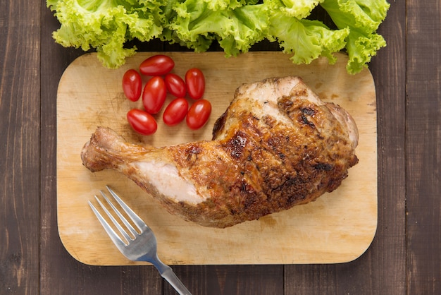 Marinated grilled chicken thigh BBQ on a wooden board.