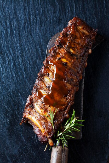 Marinated and grilled spare ribs with barbecue sauce on slate