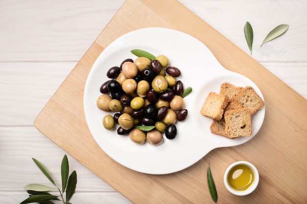 Marinated olives in plate on wooden table.