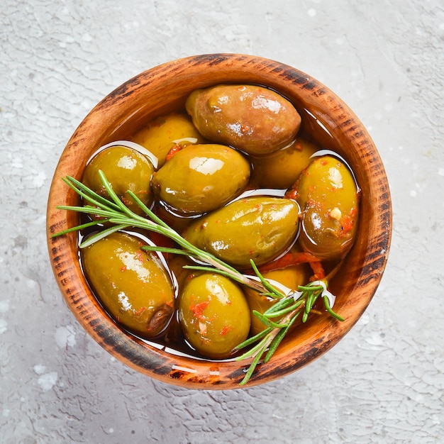 Marinated olives in a wooden bowl on a stone background Free space for text