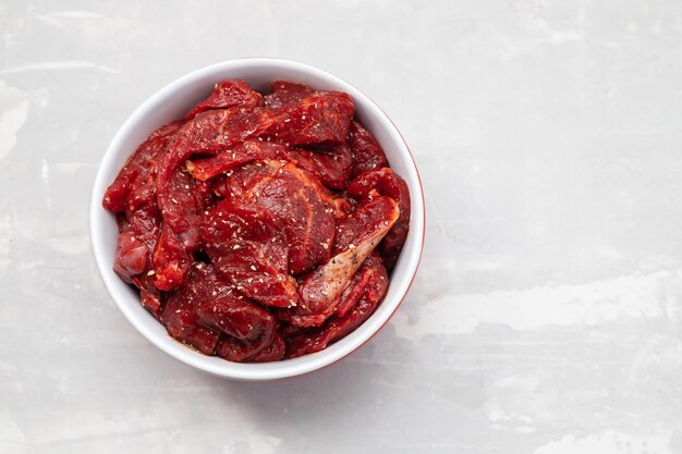 Marinated raw meat with spices in red and white bowl