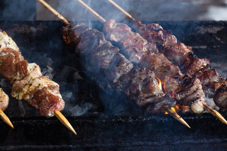 ロシアで人気のシャシリクまたはシシカバブの炭火焼きの上でバーベキューグリルで調理するマリネしたシャシリクBBQグリルでローストビーフケバブ食欲をそそる香りのよいスモーキーな肉片