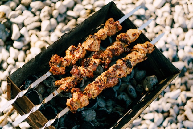 Foto shashlik marinato che si prepara su una griglia per barbecue su shashlik al carbone o shish kebab popolare in