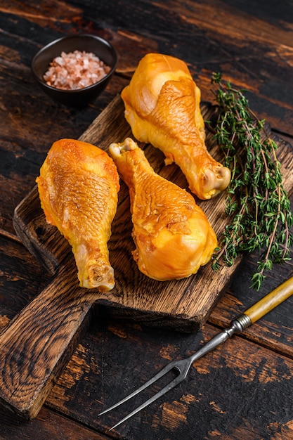 Marinated and Smoked chicken legs drumsticks on a wooden cutting board on wooden table. Top view.