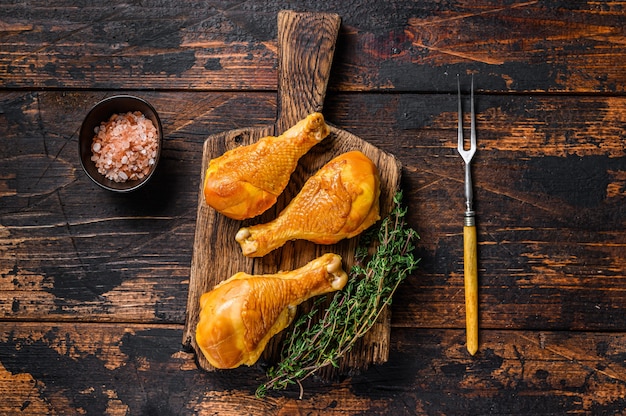 Marinated and Smoked chicken legs drumsticks on a wooden cutting board on wooden table. Top view.