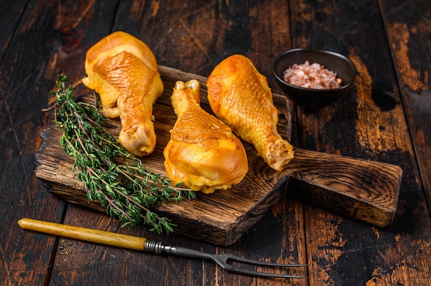 Marinated and Smoked chicken legs drumsticks on a wooden cutting board.