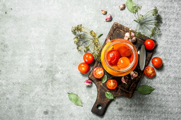 Marinated tomatoes with herbs on a stone table.