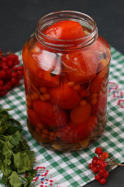 Marinated tomatoes with a viburnum in a open jar