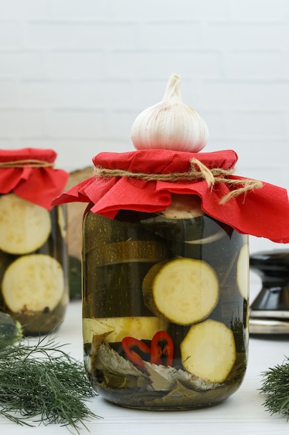Marinated zucchini in glass jars on the table on a white surface