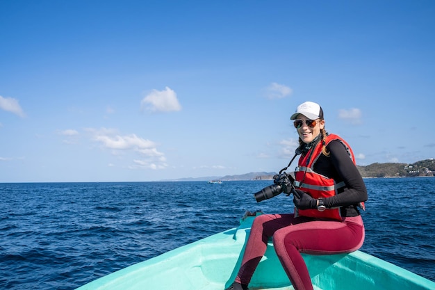 디지털 카메라를 들고 보트에 앉아 있는 해양 생물학자