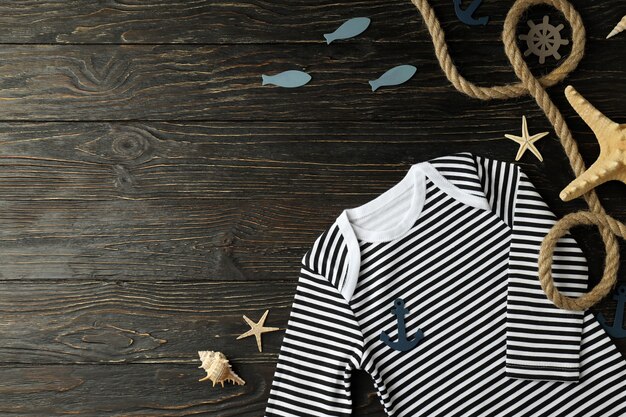 Marine concept of baby clothes on wooden background.