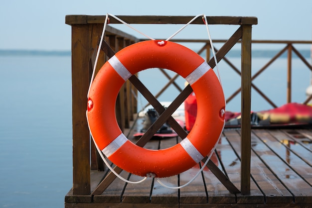 Photo marine lifebuoy on fence on water surface