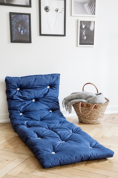 Foto marineblauw matras naast mand in wit interieur met galerij van posters aan de muur echte foto