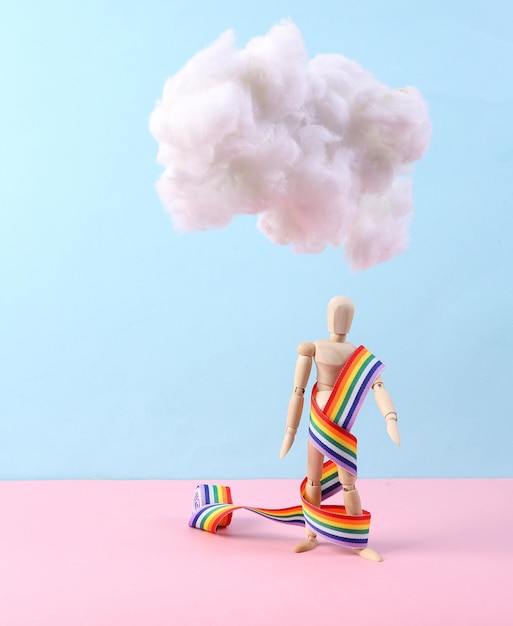 Marionet met regenboogband die pluizige wolk op pastelroze blauwe achtergrond drijft Creatief idee Minimaal lgbt-concept Pastelkleurentrend