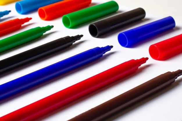 Markers of different colors at an angle on a white background caps separately