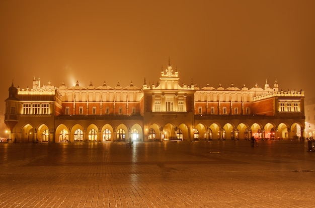 Market hall at main Cracow square at misty night with golden sky