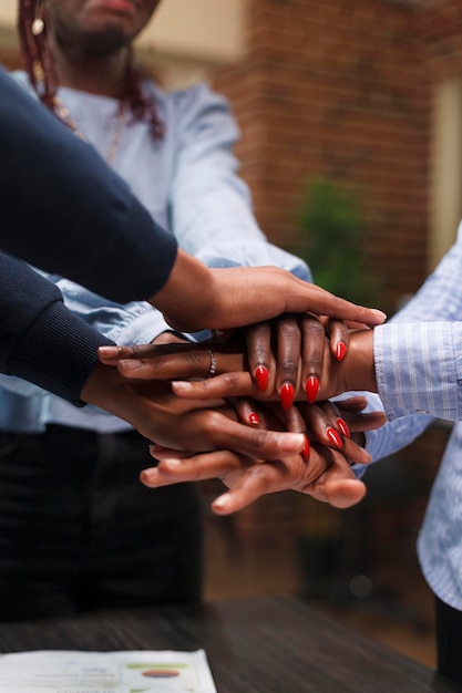 Marketing company employees celebrating successful startup\
project results and financial growth. african american financial\
department team putting their hands together to celebrate business\
success.