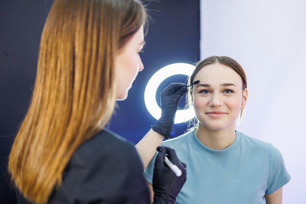 Marking a woman's face before permanent eyebrow makeup Eyebrow tattoo Beauty procedure for a woman's face