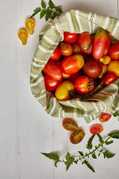 Marktlevering van verschillende soorten tomaten in eco-textielzak, nul afval, eco-achtergrond, assortiment tomaten, lokale boerenmarkt, verse groenten, oogst. Bovenaanzicht, kopieer ruimte.