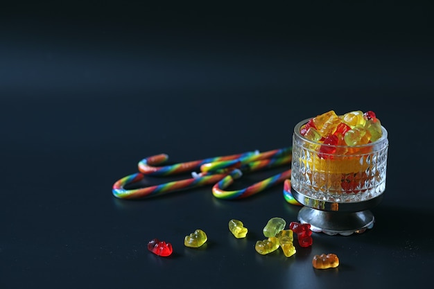 Marmalade in a vase on table. Sweets in a bowl on a black background. Multicolored jelly sweets for children.
