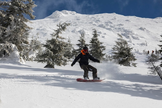 Marmarosy de Karpaten OEKRAÏNE 22 FEBRUARI 2022 Een actieve man rijdt op een snowboard freeridend op een besneeuwde helling in een backcountry alpine terrein