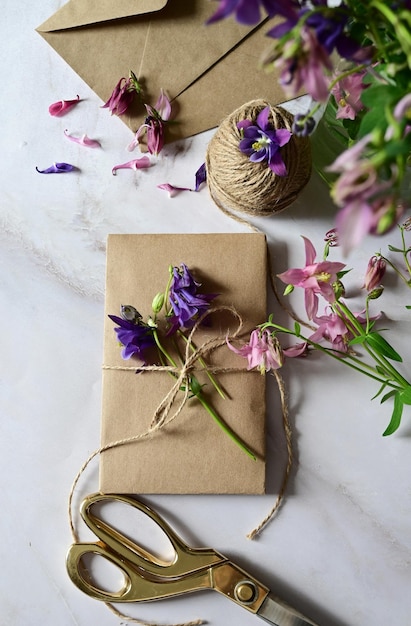 Marmeren bureau met roze en blauwe bloemen ansichtkaart kraft envelop touw katoenen tak Lay-out van Vrouwendag of Moederdag Valentijnsdag vlakke positie bovenaanzicht