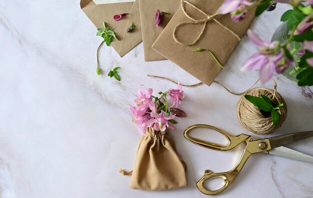 Marmeren bureau met roze en blauwe bloemen ansichtkaart kraft envelop touw katoenen tak Lay-out van Vrouwendag of Moederdag Valentijnsdag vlakke positie bovenaanzicht