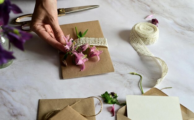 Marmeren bureau met roze en blauwe bloemen ansichtkaart kraft envelop touw katoenen tak Lay-out van Vrouwendag of Moederdag Valentijnsdag vlakke positie bovenaanzicht