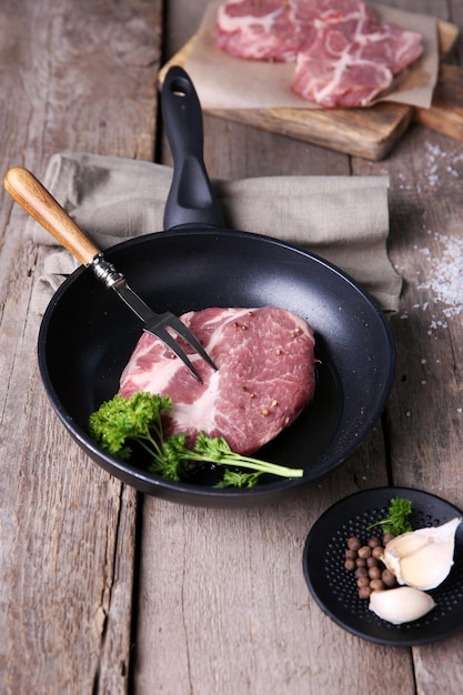 Marmeren rundvlees op een pan en specerijen op een houten achtergrond