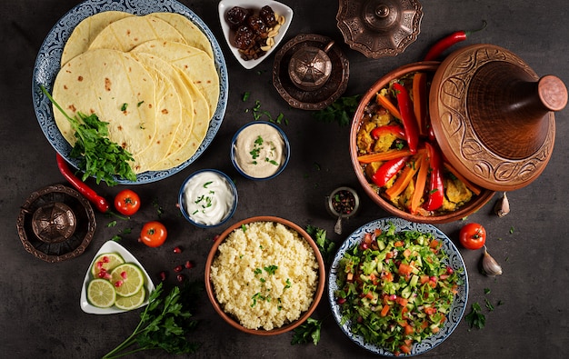 Marokkaans eten. Traditionele tajine gerechten, couscous en verse salade op rustieke houten tafel. Tajine kippenvlees en groenten. Arabische keuken. Bovenaanzicht Plat leggen