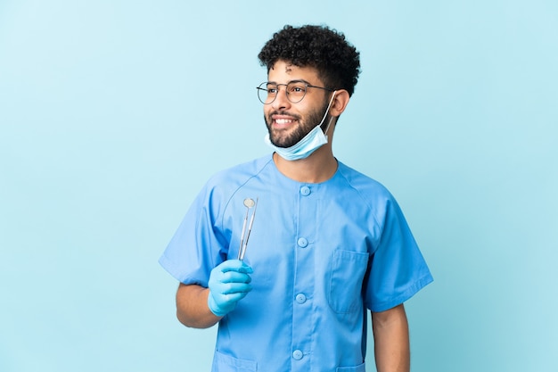 Marokkaanse tandarts man met tools geïsoleerd op blauw uitziende kant