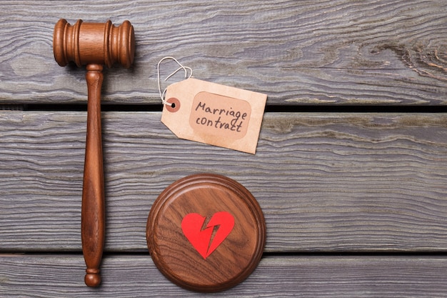 Marriage contract break up concept. Wooden gavel with broken heart on wooden desk.